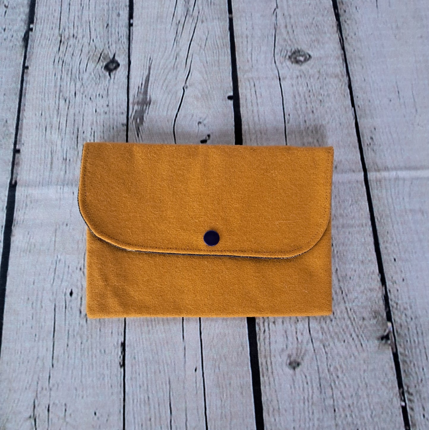 Estuche multiusos - Handcrafted mustard yellow multipurpose pouch with button closure on white wooden background. Sustainable and eco-friendly accessory made from natural materials, perfect for storing documents, cards, and makeup.